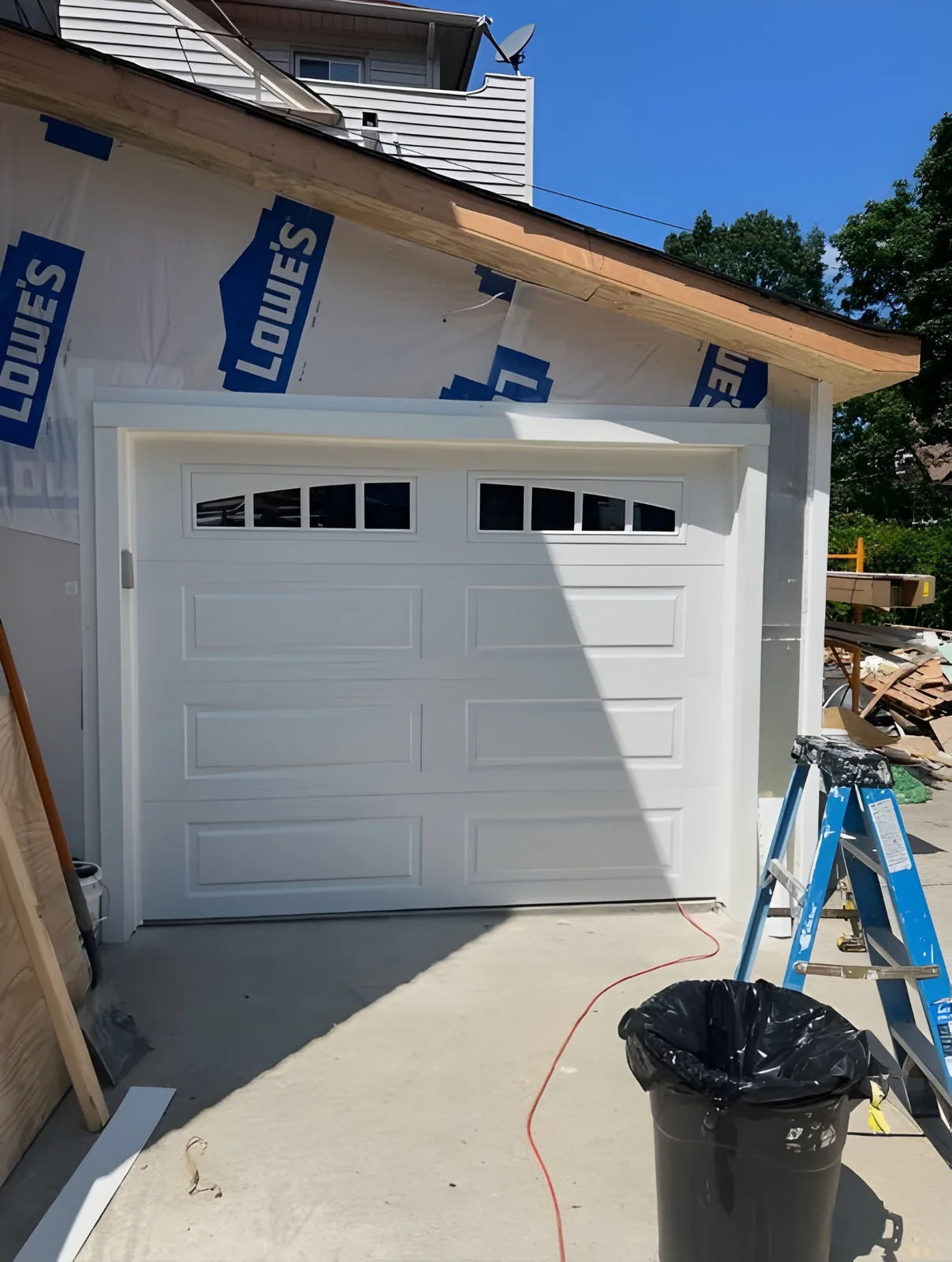 White carriage-style garage door with decorative arched windows during installation